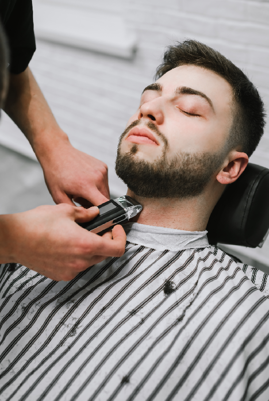 Barber shaping a client’s beard in Stafford Texas
